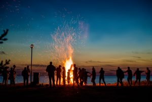 People resting near big bonfire outdoor at night